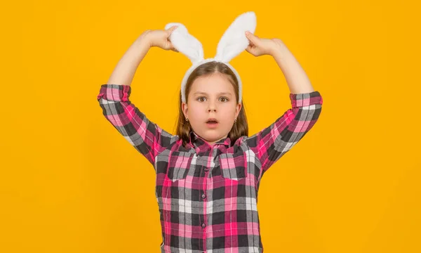 Здивована великоднім дитиною в вухах кролика на жовтому фоні — стокове фото