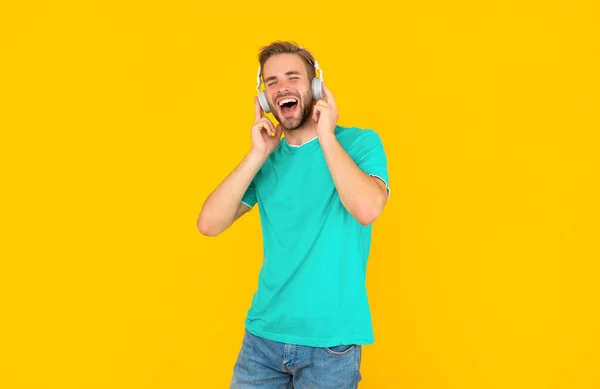 Homem alegre na camisa azul usar fones de ouvido no fundo amarelo, estilo de vida — Fotografia de Stock