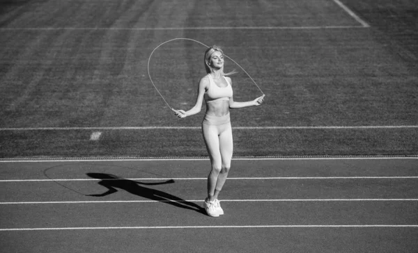 Entrainement entraîneur ou coach avec corde à sauter. sain et sportif. femme de fitness sexy en vêtements de sport. dame athlétique utiliser la corde à sauter sur le stade. athlète féminine faire de l'entraînement sportif de saut — Photo