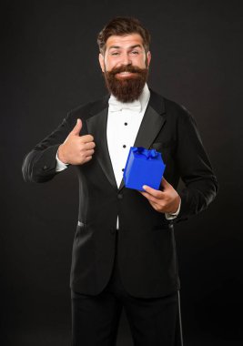 Smokinli, papyon takan, siyah arka planda, kutulu mutlu bir adam. Doğum günü. başparmak yukarı