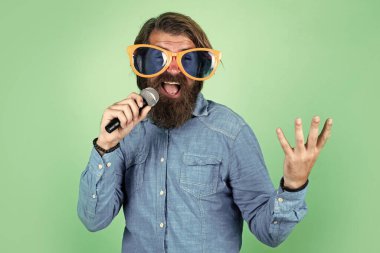 Yüksek sesle konuş. Mikrofonlu erkek hoparlör. Sesli. Mutlu gülümseyen olgun adam. Sakallı adam mikrofonda şarkı söylüyor. Vahşi Kafkas hipster etkinlik yöneticisi. Komik parti gözlükleri. karaoke ve müzik