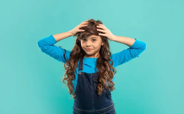 Criança engraçada com cabelos longos encaracolados no fundo azul, cuidado com o cabelo — Fotografia de Stock