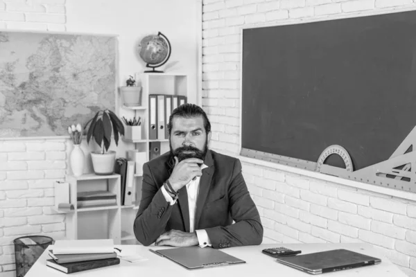 Зрелый бородатый мужчина учитель в костюме сидеть в классе школы с доской, обратно в школу — стоковое фото