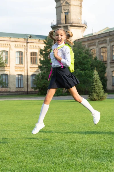 快乐精力充沛的孩子穿着校服，快乐地跳着书包，回到学校 — 图库照片