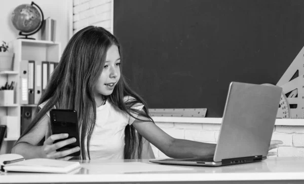 Dítě ve škole s počítačem a mobilním telefonem, výuka online — Stock fotografie