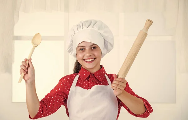 Menina criança feliz no chapéu cozinheiro e avental na cozinha, chef — Fotografia de Stock