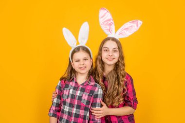 Sarı arka planda tavşan kulaklı neşeli Paskalya çocukları