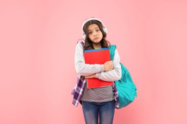 Kulaklıklı üzgün çocuk çalışma kitabını ve sırt çantasını tutuyor. Online eğitim. Okula geri dön..