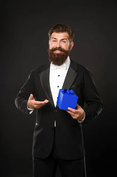 Hombre feliz en esmoquin pajarita formalwear sobre fondo negro presentando negocio recompensa caja. — Foto de Stock