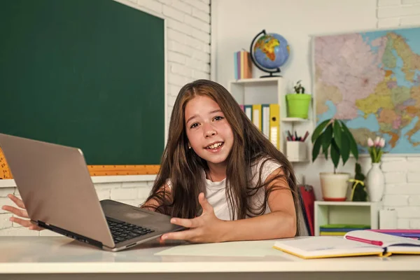 Lindo niño adolescente cerca de pizarra con portátil en la lección en línea, de vuelta a la escuela — Foto de Stock