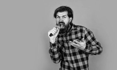 Erkek mikrofonla şarkı söylüyor. Partideki yakışıklı hippi. Müzik. Olgun bir adam şarkı söyler. Ses sınıfları. Müzik tarzı. kopyalama alanı. Sakallı adam mikrofonda şarkı söylüyor. Karaoke kulübündeki vahşi adam. Boşluğu kopyala