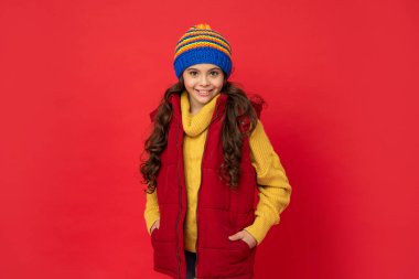 Kış modası. Şapkalı, kıvırcık saçlı mutlu çocuk. Kadın manken. Yelek giyen genç kız..