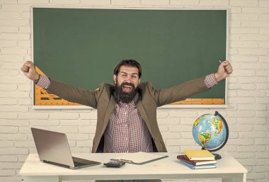 Kostümlü olgun sakallı adam öğretmen. Sınıfta coğrafya haritası ve tatille otur.