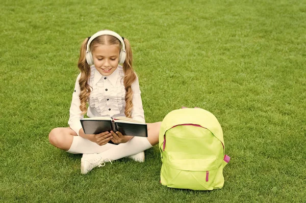 Dil öğrenme kursu. Kız çocuğu yeşil çimenlerde oturarak İngilizce öğreniyor. Yabancı dil. Ses dersi — Stok fotoğraf