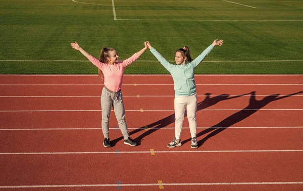 Os esportes realmente fortalecem a amizade. Os amigos felizes dão as mãos na pista de atletismo. Conceito de amizade — Fotografia de Stock