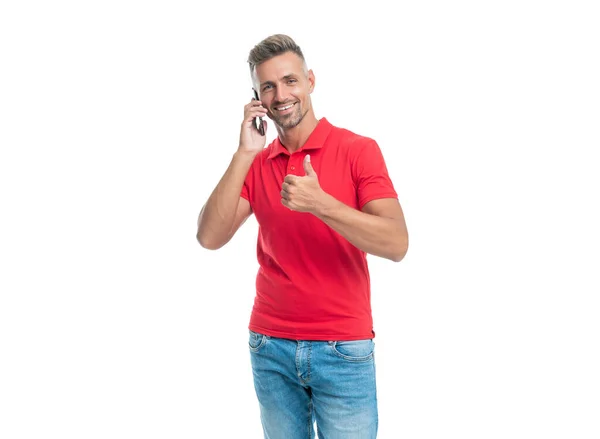 Hombre feliz en camiseta roja hablando en teléfono inteligente aislado sobre fondo blanco. Pulgar hacia arriba — Foto de Stock