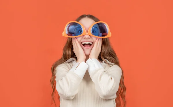 Verrast gek meisje kind dragen grote grappige bril ondersteboven bruine achtergrond — Stockfoto