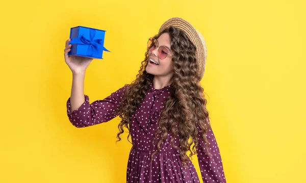 幸せな子供とともに巻き毛ホールドプレゼントボックス上の黄色の背景 — ストック写真