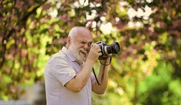 Creating memories for lifetime. Emotions through photos. Hobby and leisure. Experienced photographer in spring garden. Senior man shoot in nature. Cameraman outdoors. Photographer shooting nature — Stock Photo, Image