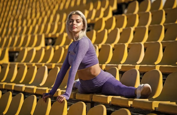 Gezondheid en energie. flexibiliteit. sexy dame in fitness sportkleding. gespleten op arena tribune. — Stockfoto