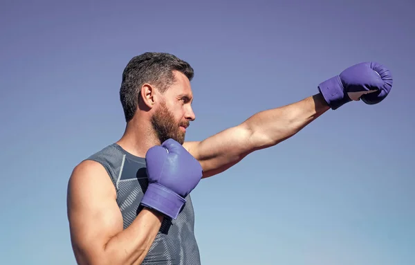 Atletik kaslı adam boksör eldivenlerle boks yapıyor, yumruk atıyor. — Stok fotoğraf
