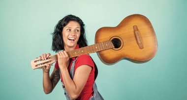 Gülümseyen, modaya uygun kıyafetleri olan, gitar çalan, gitarist bir bayan hippi.