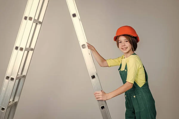Tonåring flicka arbetare i skyddshjälm och uniform på stege, byggnad — Stockfoto