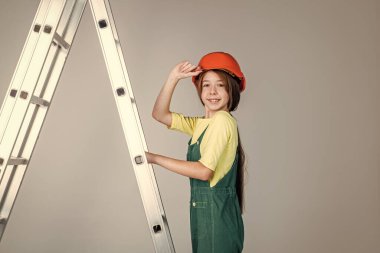 Üniformalı ve kasklı merdivenli genç bir kız. Sert şapkalı kadın müteahhit.