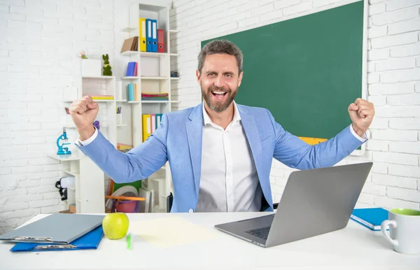 Счастливый школьный учитель в классе с компьютером за доской — стоковое фото