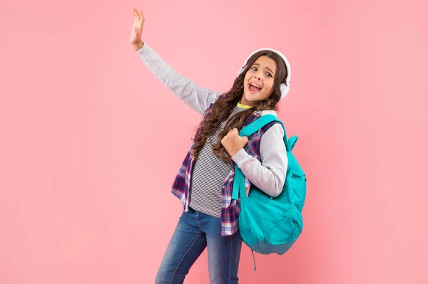 Σοκαρισμένο παιδί ακούει μουσική στα ακουστικά και να μεταφέρουν σακίδιο πλάτης σε ροζ φόντο, σύγχρονη ζωή — Φωτογραφία Αρχείου