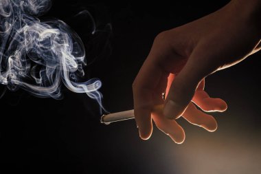 Erkek el ele tutuşması sigara yakma, dumanlı karanlık arka plan, sigara içme alışkanlığı