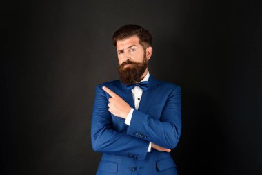 Smokin papyonlu ciddi bir adam. Siyah arka planda resmi kıyafetli bir adam işaret ediyor. Boşluğu kopyala.