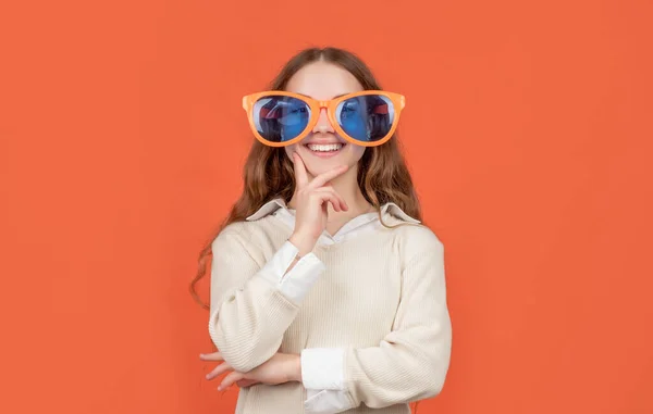 Щаслива дитина погладжує підборіддя у великих смішних сонцезахисних окулярах коричневий фон — стокове фото