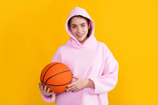 Позитивна спортивна дівчина з баскетбольним м'ячем на жовтому фоні — стокове фото