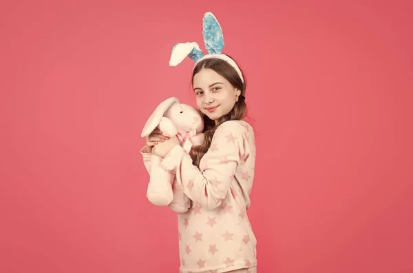 Feliz pascua niña en conejo orejas de conejo y pijama jugar con juguete, pascua —  Fotos de Stock