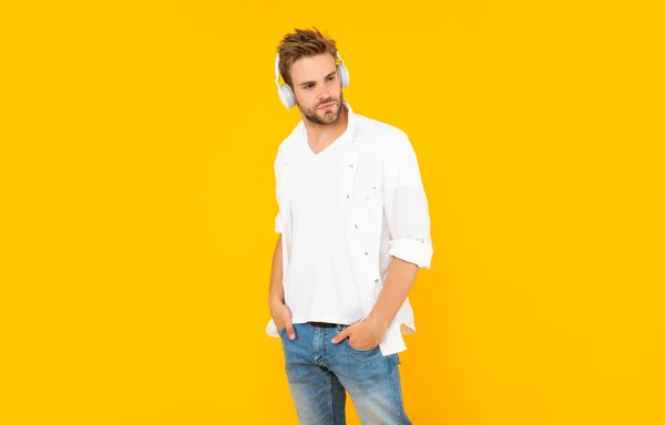 Young guy with bristle listen music on yellow background, fashion — Stock Photo, Image