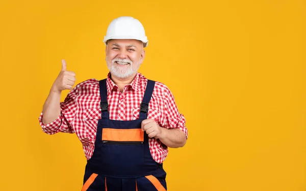 Vidám idős férfi építész sisak sárga háttér — Stock Fotó
