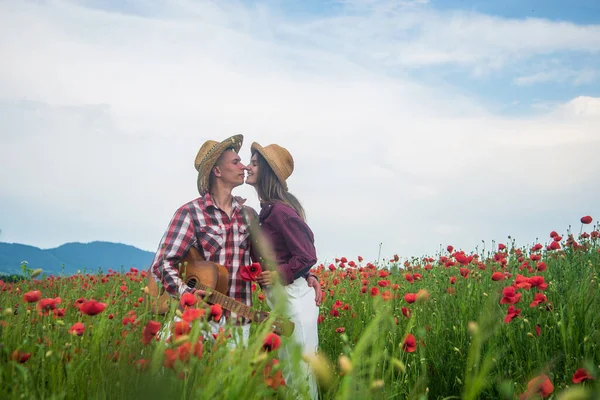 Aşık mutlu çift akustik gitarlı gelincik çiçeğinin güzel tarlasında rahatla, müziği sev. — Stok fotoğraf
