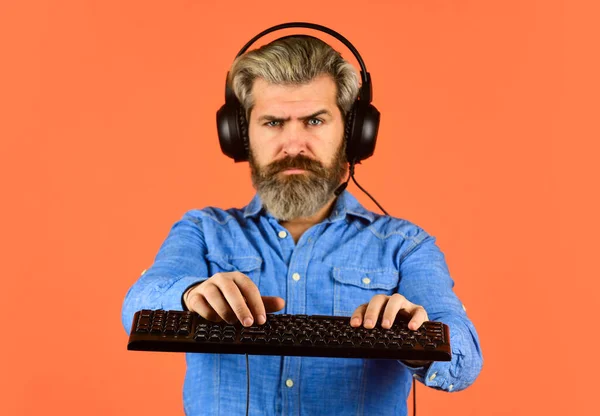 agile business. downloading music from internet. bearded man headphones and keyboard. Professional Gamer Playing Arcade computer game. chat online. Online Video Game. Cyber Championship