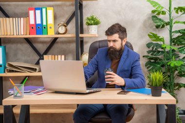 Ofiste bilgisayar ve kahve eşliğinde iş dünyasının acımasız CEO 'su, e-postayı kontrol et.