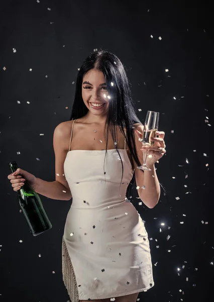 Donna glamour divertirsi sotto la caduta coriandoli. sexy donna bere champagne e vetro. — Foto Stock