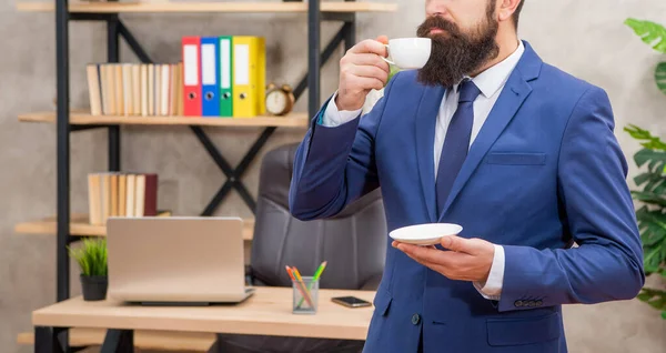 Обрезанный жестокий генеральный директор в деловом костюме пить утреннюю чашку кофе в офисе, профессиональный — стоковое фото
