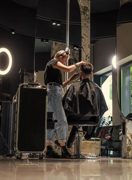Skud af frisør skære hår af smuk fyr klient, frisør betjener klient på barber butik - Stock-foto