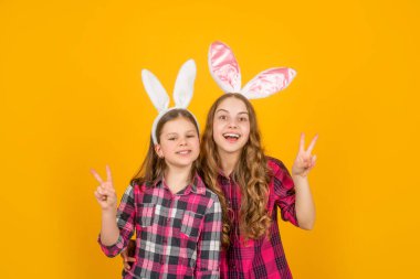 Sarı arka planda tavşan kulaklı mutlu Paskalya çocukları. Barış