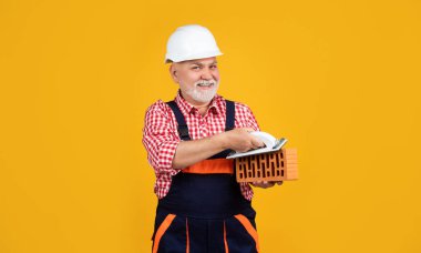 Sarı arka planda kasklı, olgun bir adam.