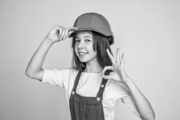 Ingeniero adolescente es trabajador de la construcción. Día internacional de los trabajadores. electricista mostrar gesto bien. chica en casco juega constructor. edificio y renovación. niño construir la construcción. ok gesto — Foto de Stock