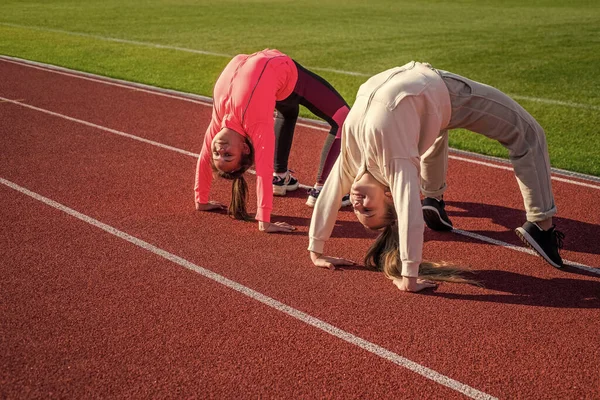 Ginastas meninas flexíveis ficar na posição de caranguejo na pista de atletismo, flexibilidade — Fotografia de Stock