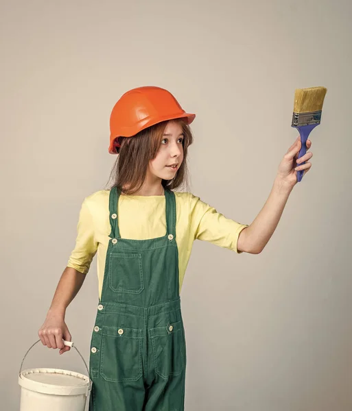 Κορίτσι παιδί σε σκληρό καπέλο στο εργοτάξιο χρησιμοποιούν βούρτσα ζωγραφικής, οικοδόμος — Φωτογραφία Αρχείου
