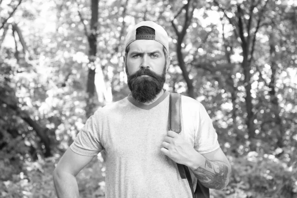 Homem barbudo maduro com barba e bigode na camisa de verão e tampa segurar mochila na floresta, viajante — Fotografia de Stock