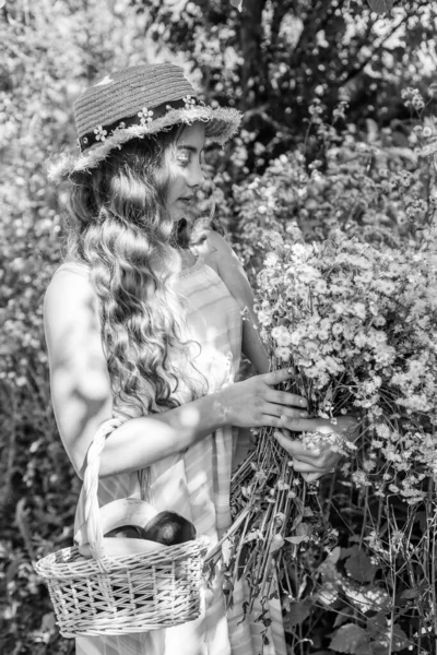 Menina pequena com cabelos longos ondulados em chapéu de sol pegar frutas e flores no jardim de verão, fazenda — Fotografia de Stock